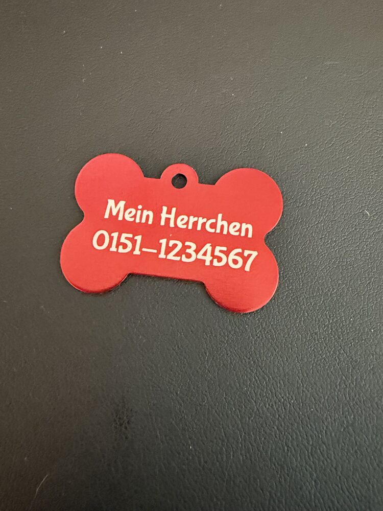 Rückseite der roten Knochen-Hundemarke mit Kontaktdaten